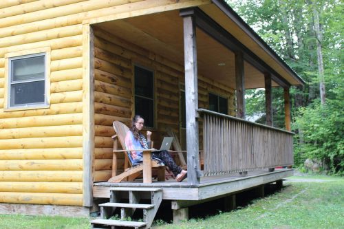 Girl on Sterling Ridge cabin front porch working from home