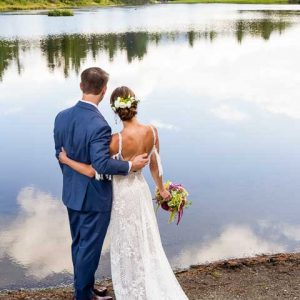 bride and groom looking out at vermont pond