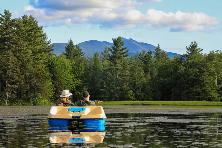 Couple in a paddleboat at sterling ridge resort with mount mansfield in the background